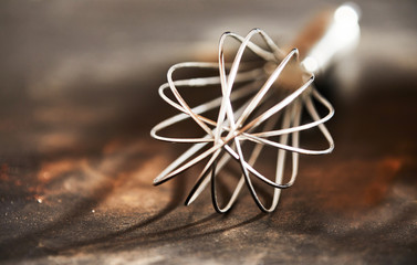 Fototapeta na wymiar Old vintage steel wire whisk on a kitchen table