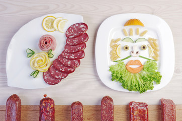 Meat eating or vegetarianism? Plate with sausages and a plate with salad and vegetables, decorated...