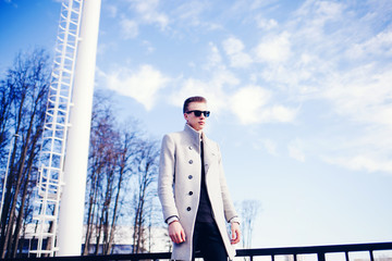 Portrait of elegant fashionable young man dressed in coat in sunny day