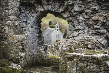 A small church seen through the Hole in the Wall (most likely a window in its time) at the ruins of Rock of Dunamase, in county Laois, Ireland  