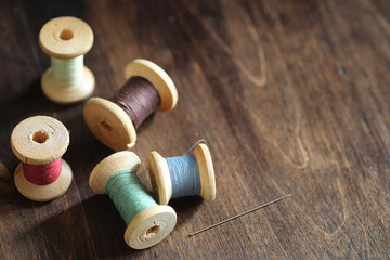 Sewing thread on a wooden background. Set of threads on bobbins retro style. Vintage accessories for sewing on the table.