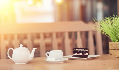 Kettle with a drink and dessert in a street cafe. Tea in the kettle cup on the table. Breakfast with tea and cakes at the cafe.