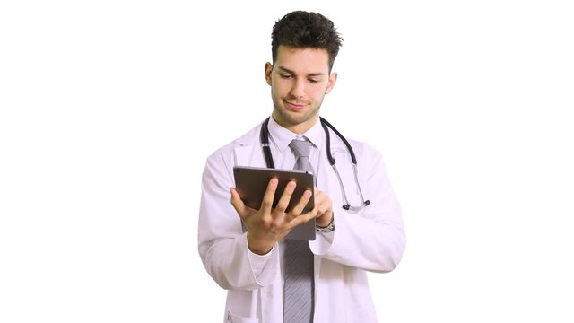 Serious doctor man browsing a tablet isolated on white background