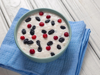 Oatmeal with raisins and cranberries on a wooden white table . Healthy food