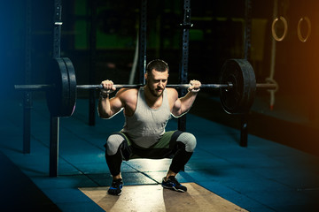 Fototapeta na wymiar Man with heavyweight barbell in the dark gym.