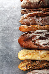 Assortment of baked bread and bread rolls on stone table background