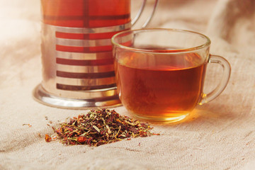 Cup of hot black tea, dried tea leaves on a light sackcloth background