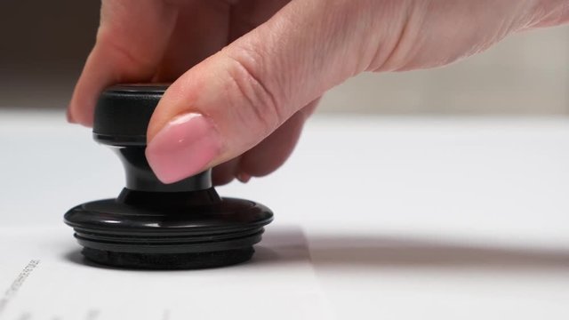 Business woman puts a stamp on the document and signs. Close-up.