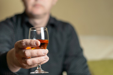 Men's hand holding a brandy glass. Man out of focus