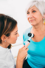 Doctor examining patient skin moles with dermoscope