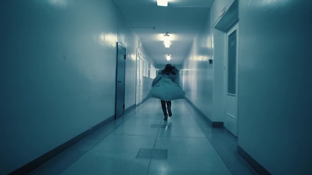 A young excited woman in a panic runs away from her pursuer along a dark corridor. A flickering sign with Russian text above the doors: exit.