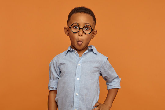 Human facial expressions, emotions, feelings and reaction. Funny nerdy African American ten year old kid wearing round glasses opening eyes widely, surprised with unexpected astonishing news