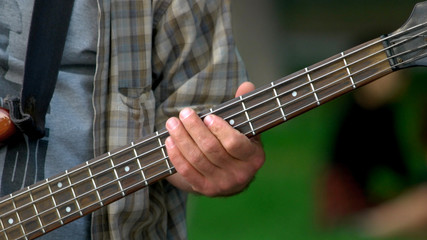 Male fingers holding guitar outdoors. Close up fingers of mature man on fret of acoustic guitar....