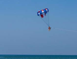 parasail with two swimmers hanging above the ocean while being pulled by motor boat