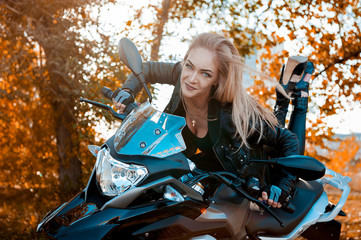 Fototapeta na wymiar Attractive young woman in black leather outfit with classic style motorcycle.