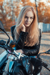Fototapeta na wymiar Attractive young woman in black leather outfit with classic style motorcycle.