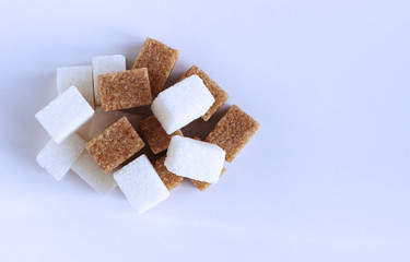Brown cane sugar and white sugar cubes on white background