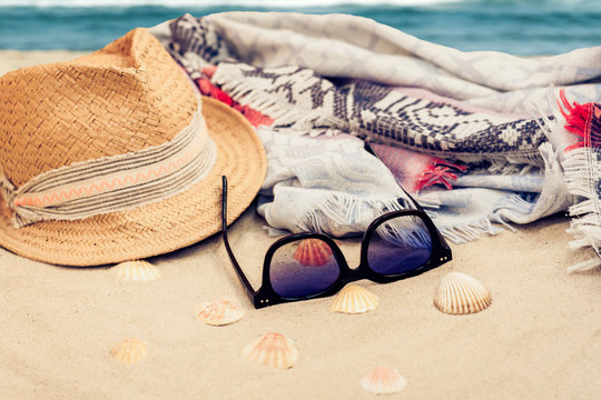 Straw hat, cover-up beachwear wrap and sun glasses on a tropical beach .