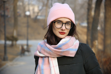 portrait of a cute girl with glasses and a hat on the street
