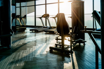 treadmills row in fitness gym with window and sunset background