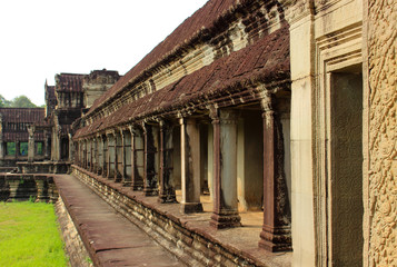 Fototapeta na wymiar Exterior a open stone gallery or corridor of Angkor Wat temple at Siem Reap, Cambodia. Largest religious monument in the world and popular tourist attraction. Object a UNESCO World Heritage Site.