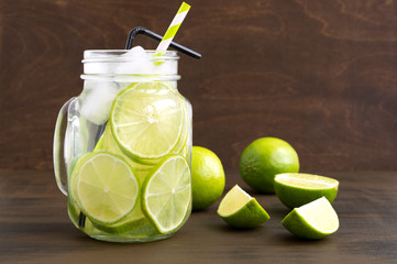 Mason jar glass of lemonade with lime and straw on wooden background-image