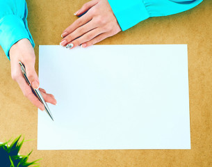 Blank paper lying on the table and waiting for idea with woman's hands over it .