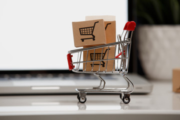paper boxes in a shopping cart on a laptop keyboard. Concepts about online shopping that consumers...