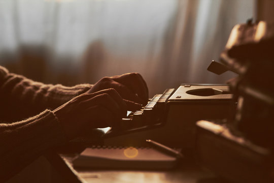 Young man writing on old typewriter.