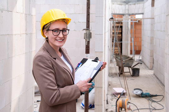 Frau als Architektin, Ingenieurin mit Helm, Bauplan, Pl&auml;nen auf einer Baustelle mit Kran