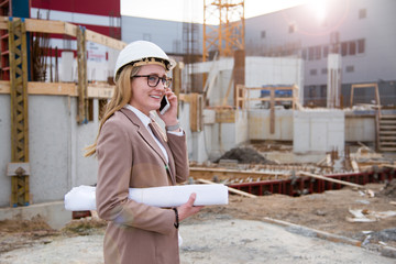 Frau als Architektin mit Helm, Bauplan, Plänen auf einer Baustelle mit Kran