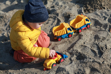 boy playing on the sandpit with construction cars