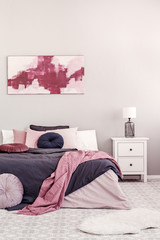 Abstract white and burgundy painting on the wall of stylish bedroom interior with king size bed