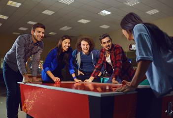 A group of friends playing air hockey.