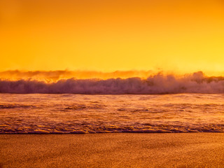 Waves splashing on a beach during sunset