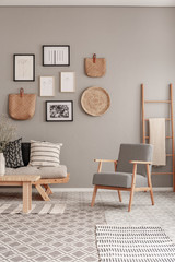 Trendy vintage armchair next to chic scandinavian sofa with pillows in classy living room interior © Photographee.eu