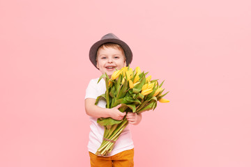 Adorable smiling child with spring flower bouquet looking at camera isolated on pink. Little...
