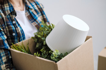 Young beautiful girl with colored hair in a white T-shirt, plaid shirt and jeans, against the background of cardboard boxes and things.