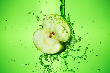 Apple splashing juice, water, on a green background.
