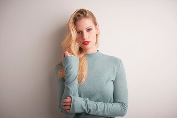 Studio portrait of beautiful young woman standing at light grey background