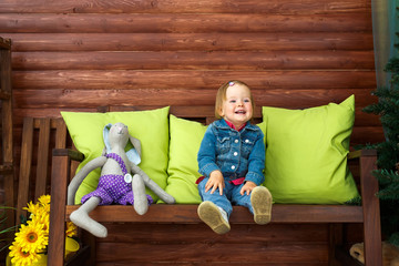 The little girl is sitting and smiling.