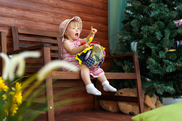 The little girl is sitting and smiling.
