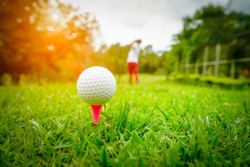Golf ball on tee in beautiful golf course at sunset background. Golf ball on green in golf course at Thailand