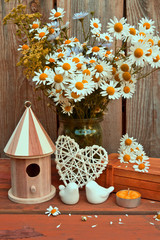 Porcelain birds, a birdhouse and a bouquet of chamomiles