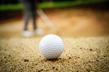 Golf ball on sand bunker in beautiful golf course at sunset background. Golf ball on green in golf course at Thailand