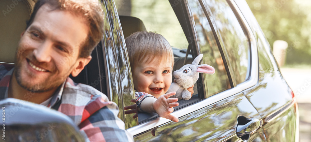 Wall mural It's time for another adventure. Cute little caucasian boy sitting inside the car and looking out the window. Family road trip