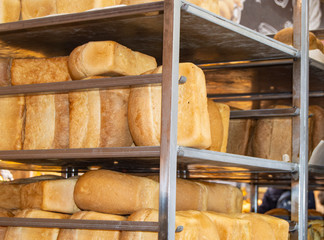 The ranks of the hot crispy bread loaves lying on a shelf in a supermarket, a bakery, a background...