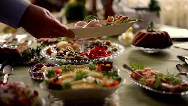 Hand putting platter with ham on table, super slow motion