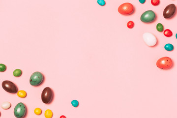 Easter frame made from colorful eggs and big chocolate egg flat lay on white background. Top view, copyspace for text.