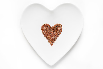 flax seeds lies in the shape of a heart on a white plate